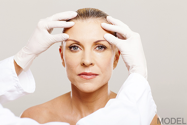 Doctor examining woman's forehead